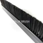 Tufted strip brush with black bristles and rigid profile
