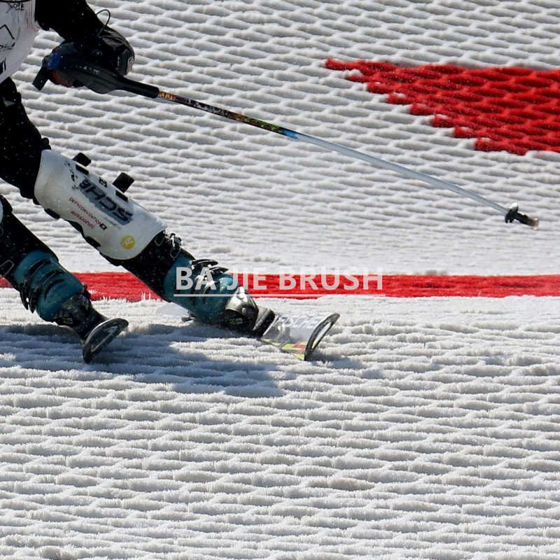 Artificial dry ski slope surface made from PBT strip brush mats