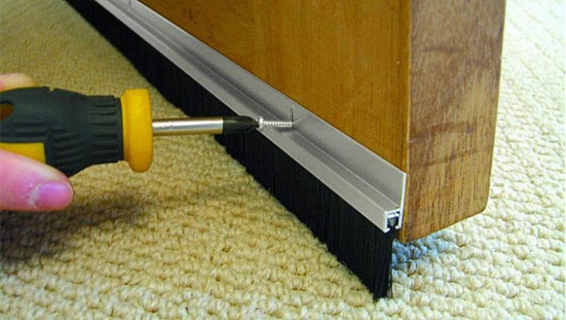 Installing a Nylon Door Bottom Sweep Brush Nylon door bottom sweep brush being fastened to a wooden door with screws