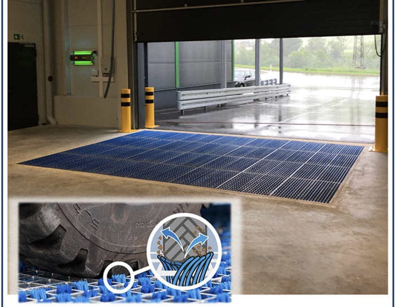 Wheel cleaning brush mat installed across an indoor loading bay entrance