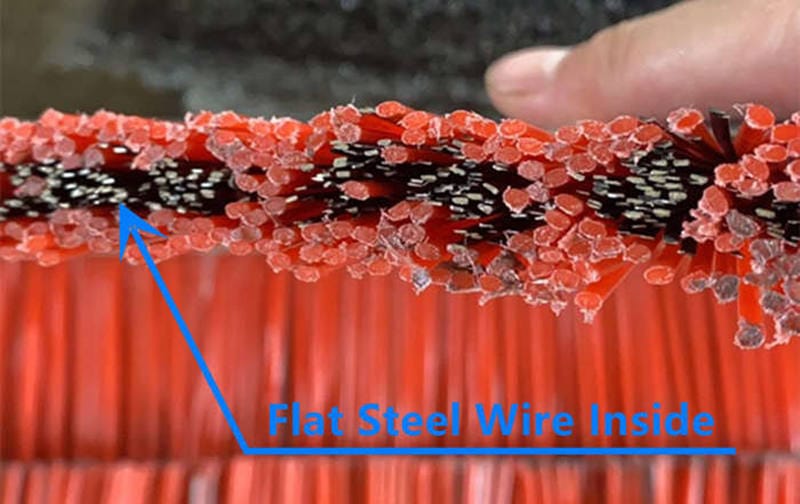 Close-up of red polypropylene filaments mixed with black flat steel wire inside a concrete block cleaning brush