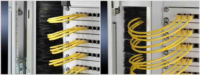 Yellow network cables passing through black vertical brush strips inside a server rack enclosure