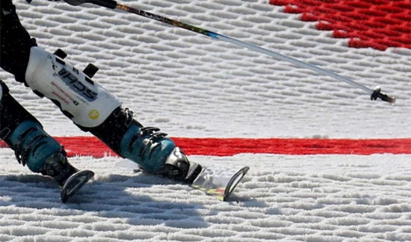 Skier using a brush-based artificial dry ski slope surface